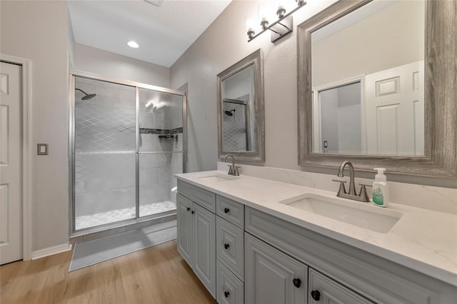 bathroom featuring hardwood / wood-style floors, vanity, and a shower with shower door