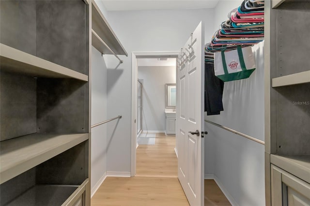 walk in closet with light hardwood / wood-style floors