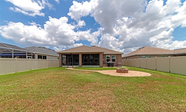 back of house featuring a patio, a sunroom, a lawn, a lanai, and a fire pit