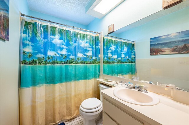 bathroom featuring tile patterned flooring, vanity, a textured ceiling, and toilet