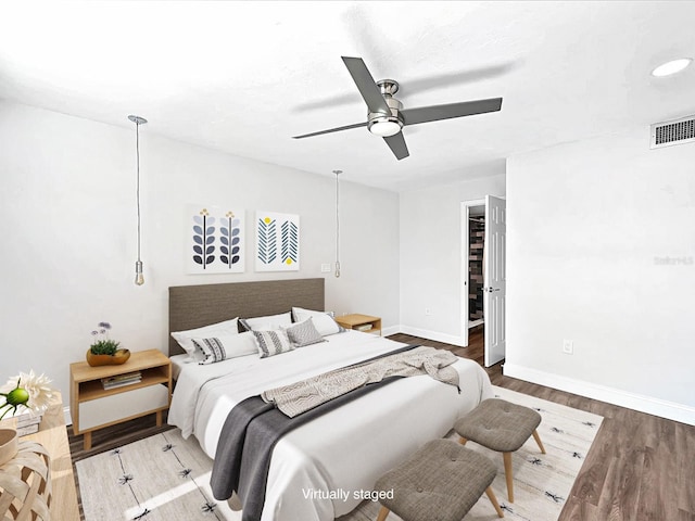 bedroom with hardwood / wood-style flooring, a walk in closet, and ceiling fan