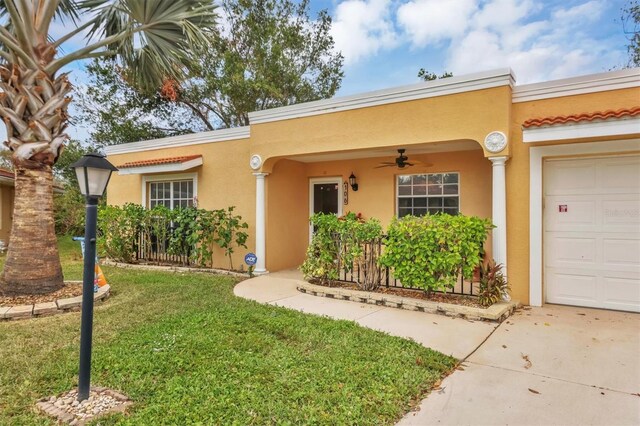 view of front of home featuring a front lawn, a garage, and ceiling fan