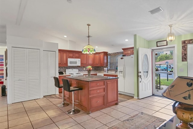 kitchen featuring light tile patterned floors, decorative light fixtures, white appliances, a kitchen island, and vaulted ceiling