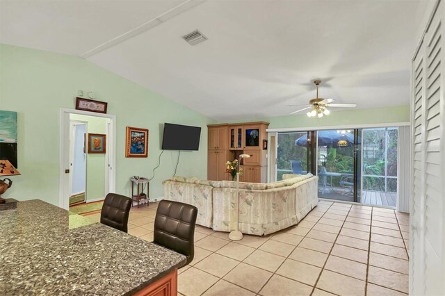 living room featuring lofted ceiling, light tile patterned floors, and ceiling fan