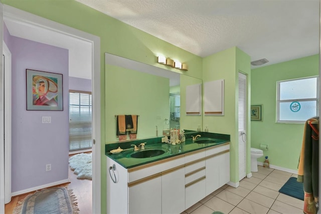 bathroom featuring tile patterned floors, vanity, a textured ceiling, and toilet