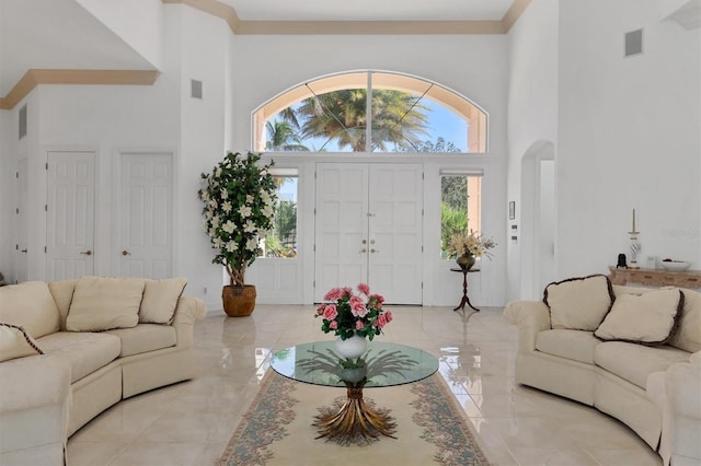 living room with a towering ceiling and crown molding