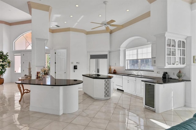 kitchen with ceiling fan, a center island, a high ceiling, built in appliances, and white cabinets