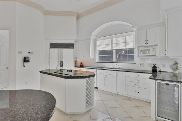 kitchen with white cabinets, a center island, built in appliances, and beverage cooler