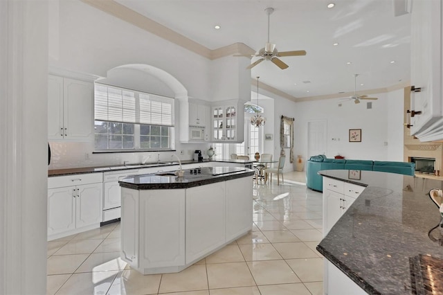 kitchen featuring decorative backsplash, a towering ceiling, white appliances, light tile patterned floors, and white cabinetry