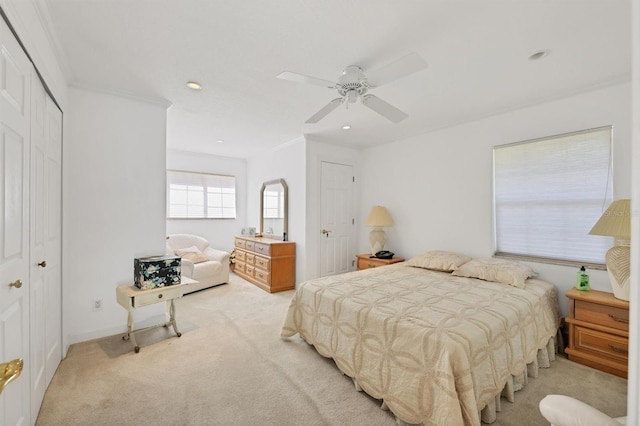 bedroom featuring a closet, light colored carpet, ceiling fan, and crown molding