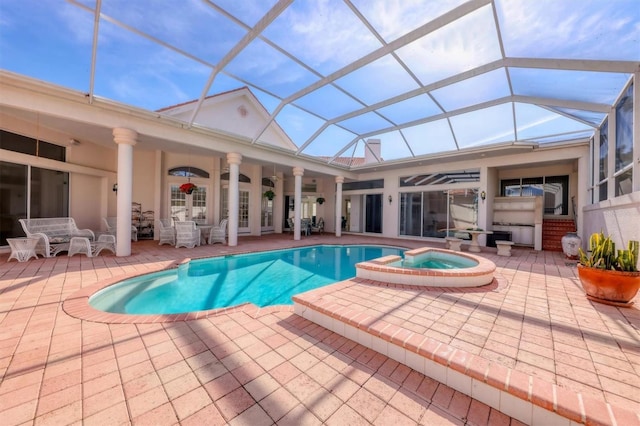 view of pool with an in ground hot tub, glass enclosure, and a patio area