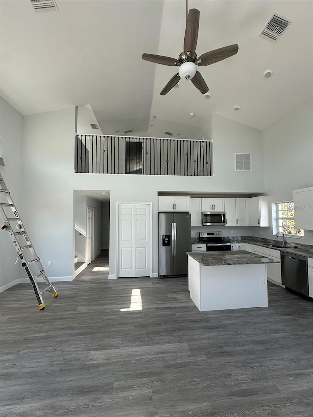 kitchen featuring appliances with stainless steel finishes, dark hardwood / wood-style floors, a kitchen island, and white cabinets