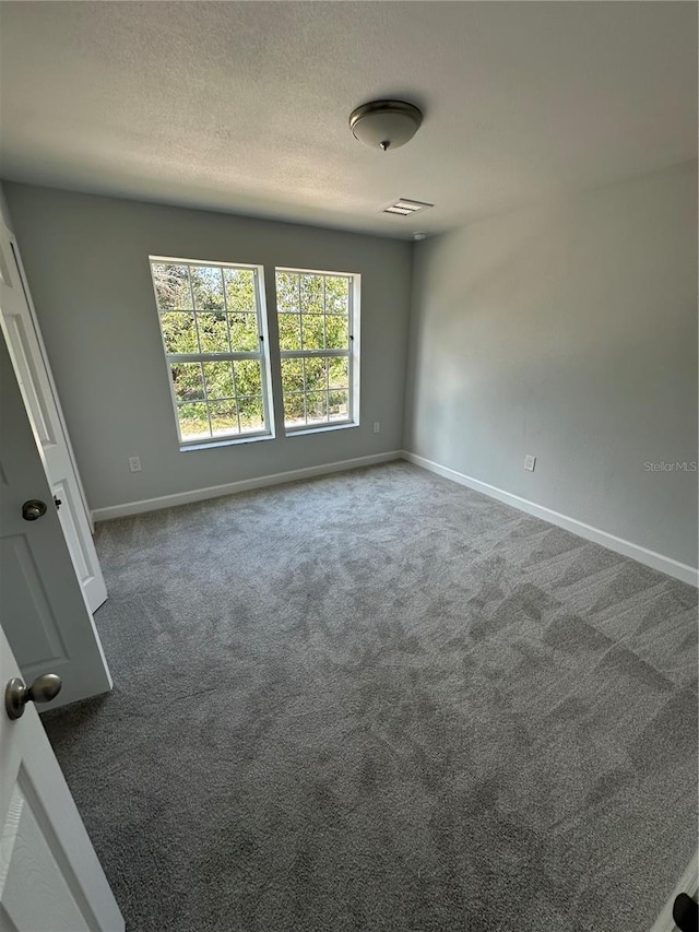 carpeted spare room with a textured ceiling