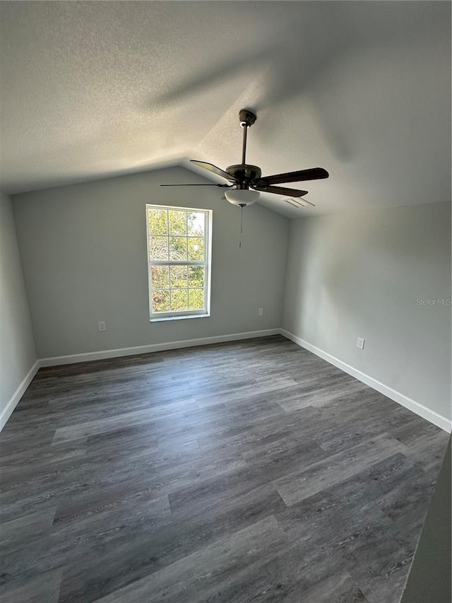 spare room with lofted ceiling, ceiling fan, dark wood-type flooring, and a textured ceiling