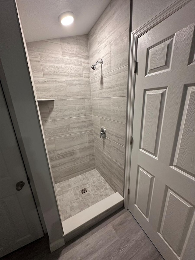 bathroom with wood-type flooring and tiled shower