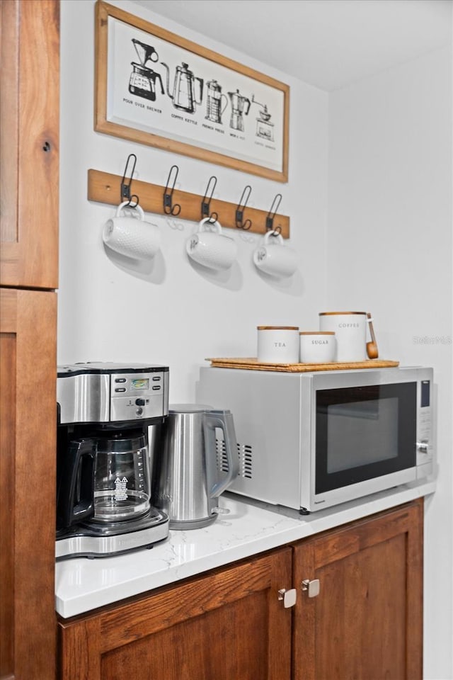 3700 S Osprey Ave Unit 214, Sarasota, FL 34239 - kitchen featuring white microwave, brown cabinetry, and light stone countertops