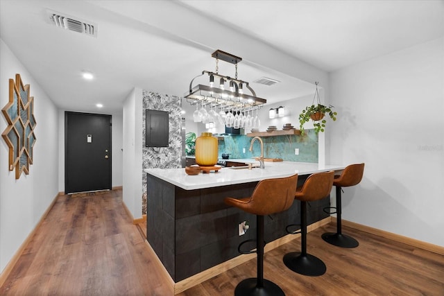 bar with tasteful backsplash, dark hardwood / wood-style flooring, sink, and pendant lighting