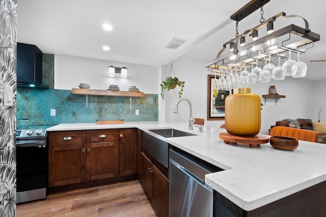 kitchen featuring dishwasher, range, kitchen peninsula, and wall chimney range hood