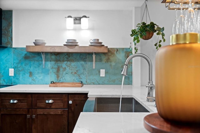 kitchen with dark brown cabinetry, tasteful backsplash, light stone counters, and sink