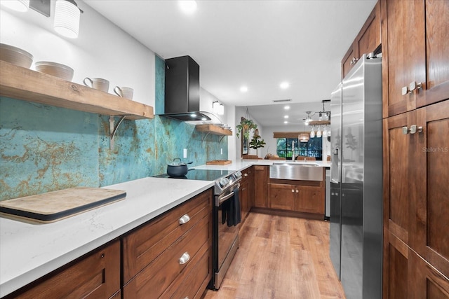 kitchen with sink, wall chimney range hood, backsplash, light hardwood / wood-style floors, and appliances with stainless steel finishes