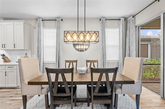 dining room with an inviting chandelier, a healthy amount of sunlight, and light hardwood / wood-style floors