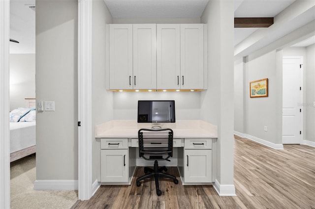 office space with built in desk and light hardwood / wood-style floors