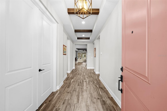 hallway featuring light wood-type flooring and a tray ceiling