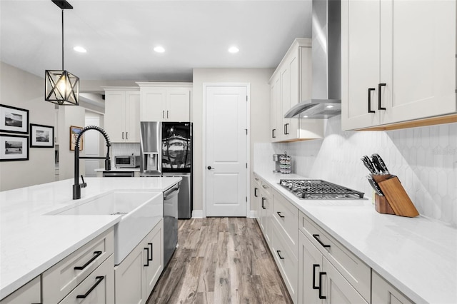 kitchen with light hardwood / wood-style flooring, white cabinetry, hanging light fixtures, and wall chimney exhaust hood