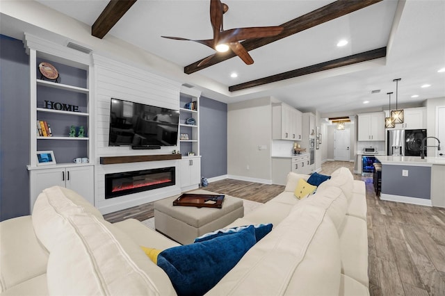 living room with ceiling fan, light wood-type flooring, and a tray ceiling