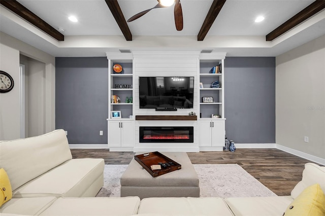 living room featuring hardwood / wood-style floors, ceiling fan, a large fireplace, and beamed ceiling