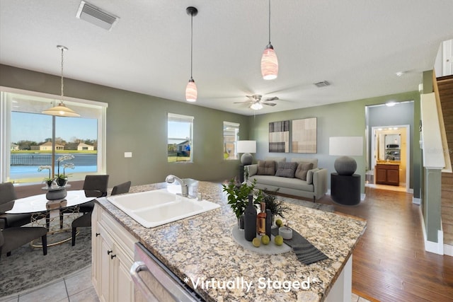 kitchen featuring light hardwood / wood-style floors, a kitchen island with sink, sink, and pendant lighting