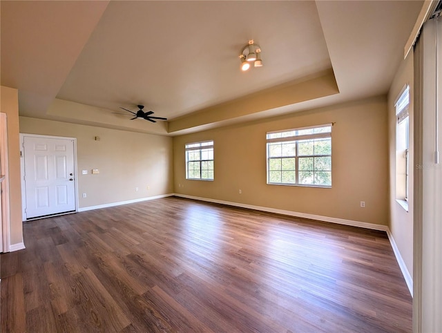 unfurnished room with ceiling fan, dark hardwood / wood-style floors, and a raised ceiling