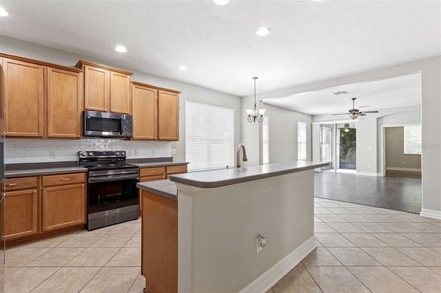 kitchen with electric stove, an island with sink, light tile patterned flooring, and ceiling fan with notable chandelier