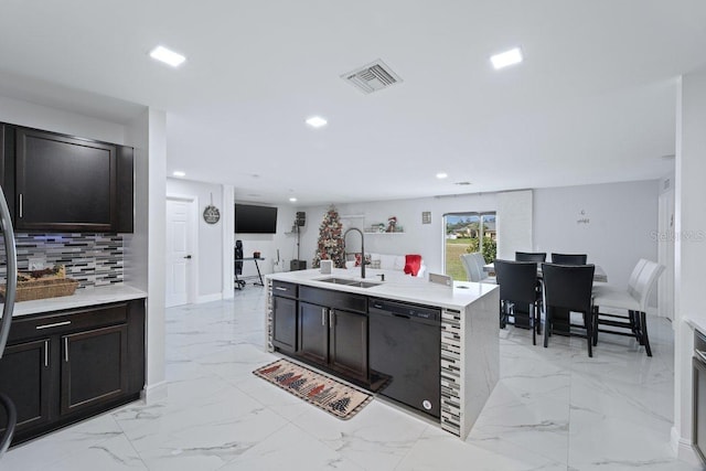 kitchen featuring sink, backsplash, an island with sink, dark brown cabinets, and black dishwasher