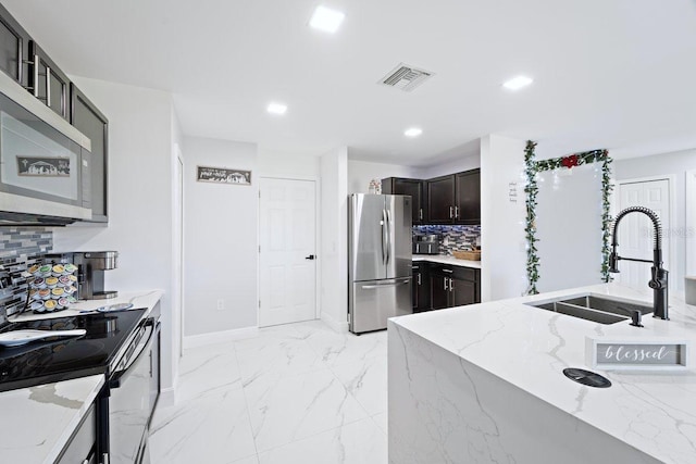 kitchen with stainless steel appliances, light stone countertops, sink, and decorative backsplash