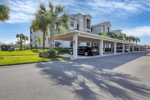 view of parking / parking lot with a carport and a yard