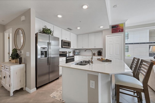 kitchen featuring a center island with sink, sink, appliances with stainless steel finishes, crown molding, and white cabinets