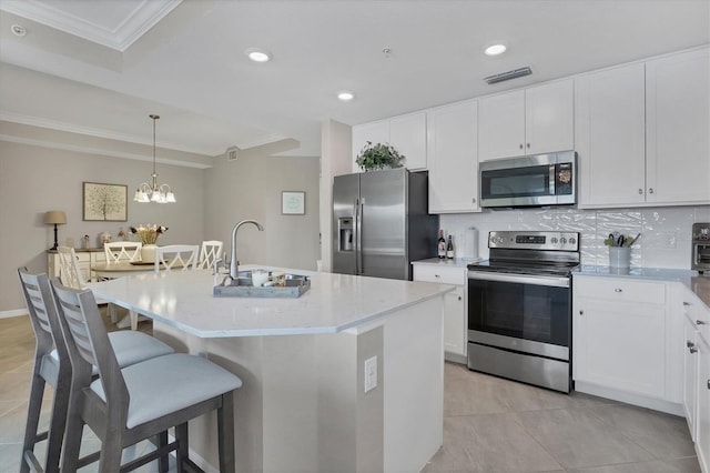 kitchen with stainless steel appliances, a center island with sink, decorative light fixtures, and tasteful backsplash