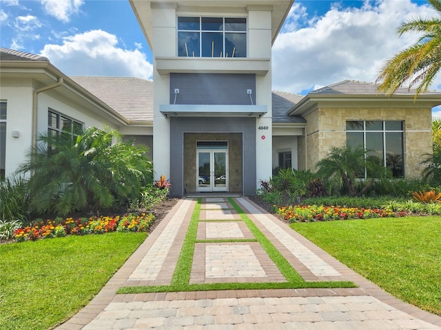 property entrance featuring a lawn and french doors