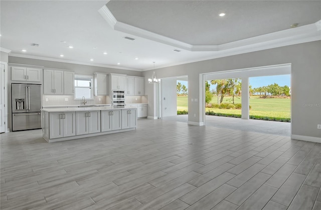 kitchen with sink, white cabinetry, built in fridge, a kitchen island, and pendant lighting