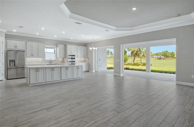 15625 San Lazzaro Ave, Bradenton, FL 34211 - kitchen with appliances with stainless steel finishes, crown molding, a center island, a raised ceiling, and a chandelier