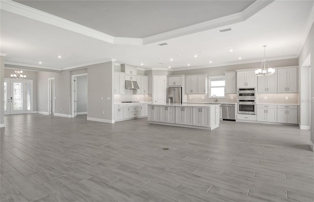 unfurnished living room featuring an inviting chandelier, crown molding, sink, and french doors