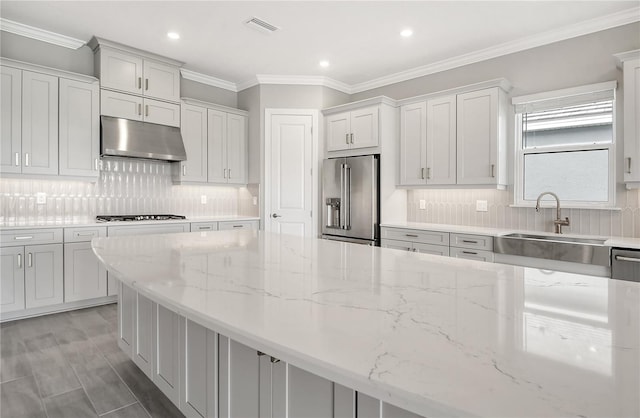 kitchen featuring sink, high end fridge, gas stovetop, light stone countertops, and white cabinets