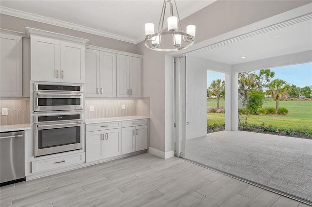 kitchen featuring white cabinetry, hanging light fixtures, stainless steel appliances, decorative backsplash, and a chandelier