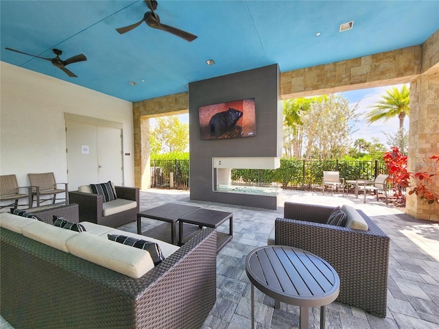 view of patio with ceiling fan and an outdoor living space with a fireplace