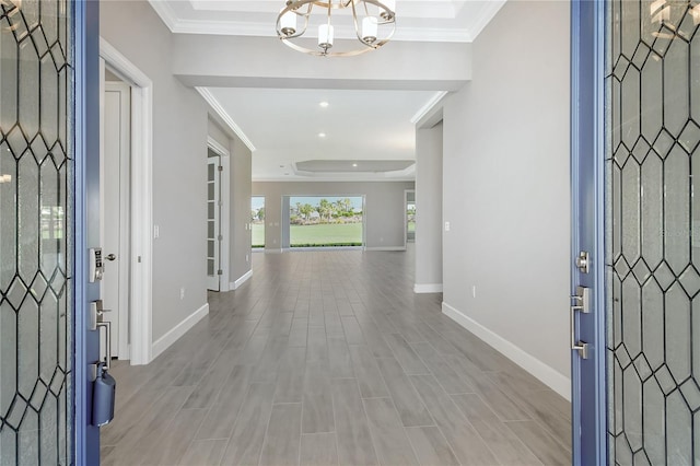 foyer entrance featuring a notable chandelier, crown molding, and light wood-type flooring