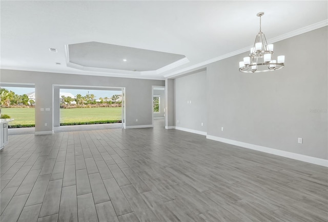 15625 San Lazzaro Ave, Bradenton, FL 34211 - unfurnished living room featuring a raised ceiling, ornamental molding, a chandelier, and wood finished floors