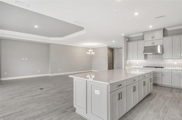 15625 San Lazzaro Ave, Bradenton, FL 34211 - kitchen with under cabinet range hood, crown molding, a chandelier, tasteful backsplash, and a center island