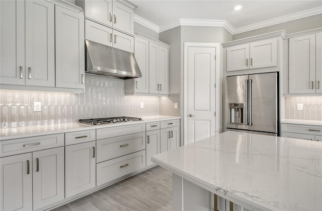 kitchen with backsplash, ornamental molding, stainless steel appliances, and light stone countertops