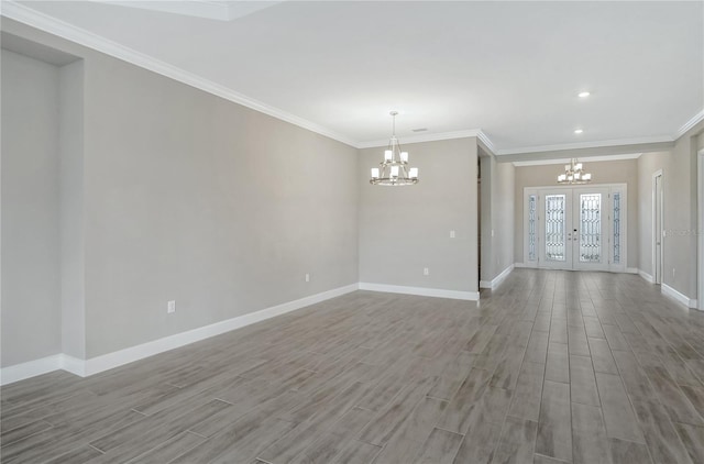 spare room with french doors, ornamental molding, and a chandelier